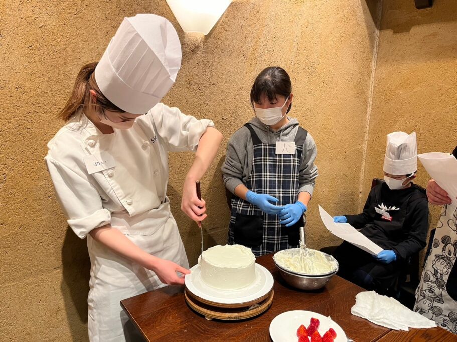 親子パティシエ体験でパティシエが参加者にナッぺのお手本を見せている様子
